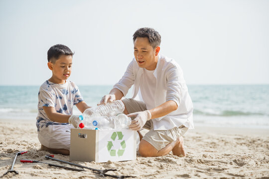 Father and son collecting plastic bottles on the beach for recycling, promoting family bonding, environmental care, and eco-friendly awareness.