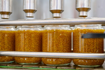 Mustard production process showcasing glass jar packaging with rich yellow mustard blend