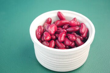 Fresh red kidney beans in a white bowl on a green surface