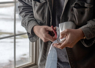 cutting plastic for window insulation with a scissors, used to help keep heat in a home during winter time 