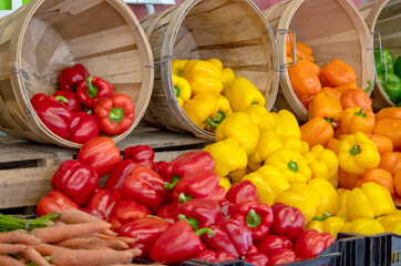 Red, yellow and orange pepper in a market, spill out of baskets to create a tempting display of veggies