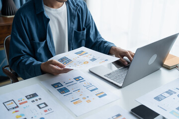 UX UI Designer Planning innovative Mobile App with Paper Wireframe Designs at Workspace.