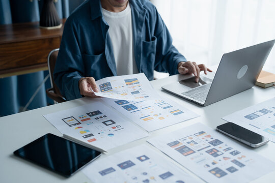 UX UI Designer Planning innovative Mobile App with Paper Wireframe Designs at Workspace.