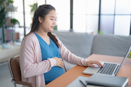 Pregnant asian woman using laptop at home pregnant businesswoman typing on laptop working on remote project in home office pregnancy