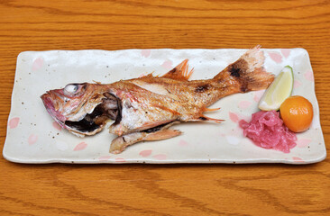Grilled rosy seabass with lemon and ginger on plate  