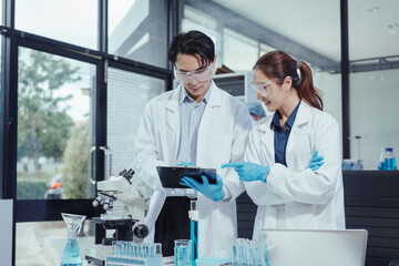 Team of Asian scientists working in modern laboratory equipped microscopes, chemical reagents,...
