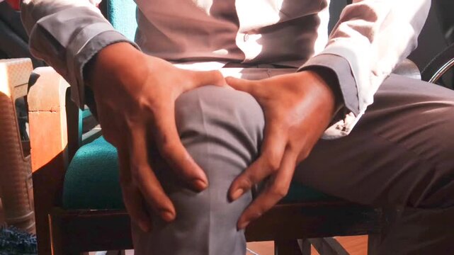 Knee pain, Asian man suffering from knee joint pain in sofa living room, bone pain in man at home, painful knee problem of man, unhappy hand holding knee pain.
