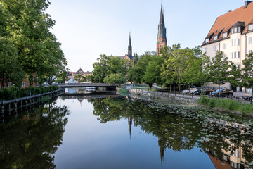 Uppsala, Sweden &ndash; Urban landscape of the city center near the Fyris River, with the Uppsala Cathedral rising in the distant background, surrounded by bridges, traditional buildings, and sunrise light.