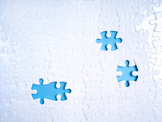 Concept of incompleteness and missing parts with three empty spaces in white jigsaw puzzle on blue...