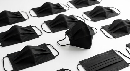 Multiple black medical masks arranged, one angled, against a white backdrop