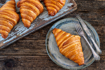 Fresh croissants in the plate at the hands of two women