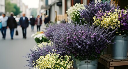 a bouquets of wildflowers spill from buckets on a city street vendor’s stall.