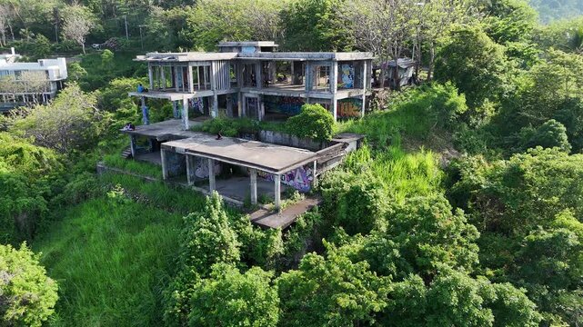 Abandoned Unfinished Concrete Building on Lush Green Hillside with Graffiti, Overgrown and Neglected Ghost Structure in Tropical Forest
