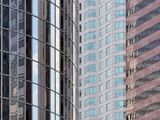 Modern office towers with reflective glass facades create geometric patterns. Buildings display various textures from sleek curtain walls to traditional stone cladding