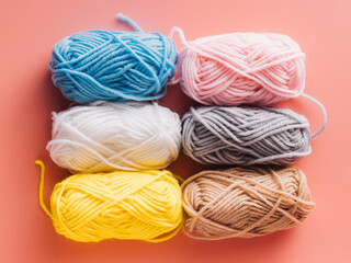 Colorful skeins of yarn arranged neatly on a pink background
