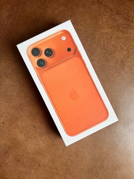 LOS ANGELES, CA, SEP 20, 2025: Box containing orange iPhone 17 Pro Max photographed from above, showing triple camera system and sleek modern design on brown surface