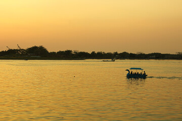 A Swan Paddle boat cruising on sunset sea from afar with scenic landscape