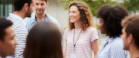Group of diverse young adults talking outdoors in a bright setting, surrounded by soft sunlight and greenery that reflect friendship, joy, and natural connection in a casual moment.