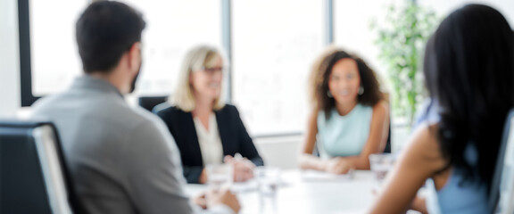 Business people meeting around a bright conference table indoors, engaged in discussion and teamwork within a modern office that reflects professionalism, leadership, and collaboration.