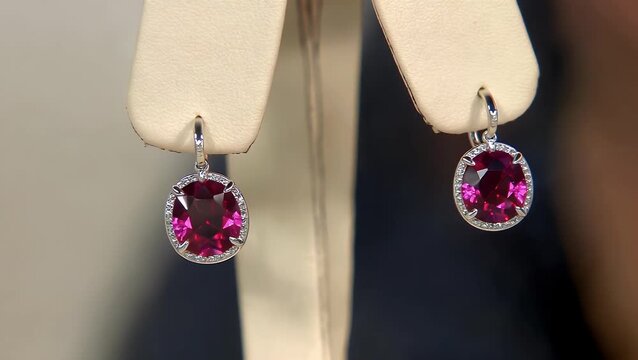 close-up view of a single precious gemstone ear accessory featuring a deep pinkish-red corundum