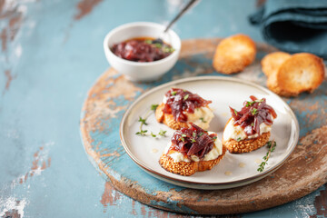 Sandwich or toast with cheese and onion marmalade on the table. French cuisine.
