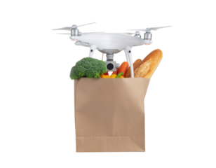 A drone carries a paper bag filled with fresh vegetables and bread.
