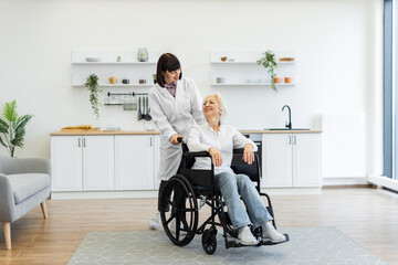 A caregiver pushes an elderly woman in a wheelchair, smiling at each other in a bright, modern...