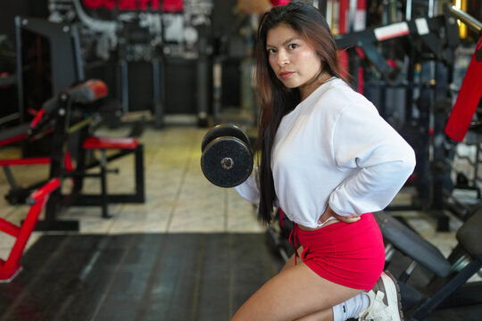 Asian woman doing dumbbell bicep curl workout in gym - Powered by Adobe
