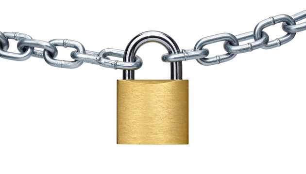A shiny gold padlock secures a heavy silver metal chain against a stark white background in a clean, simple composition