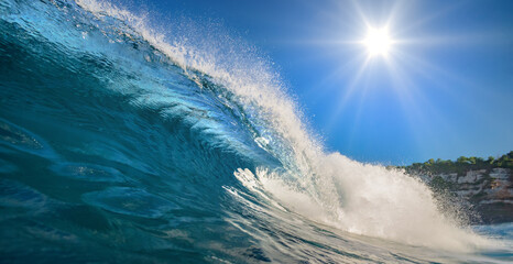 Big blue clear surfing wave at Bali under sunlight with blue sky on top