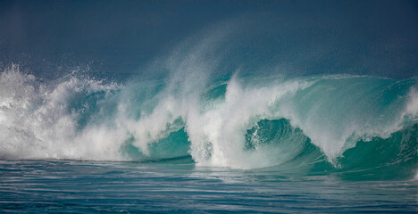 Hawaii, Oahu island at Northshore, sunrise lit big surfing crashing ocean wave with dark mist on horizon line with copyspace