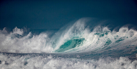Hawaii, Oahu island at Northshore, sunrise lit big surfing crashing ocean wave with dark mist on horizon line with copyspace