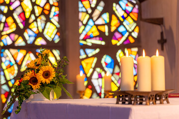 Vier weiße Flammen stehen als stille Wächter der Hoffnung, ihr sanfter Schein misst die Zeit nicht in Stunden, sondern in Augenblicken der Einkehr. Daneben trotzen die Sonnenblumen in goldener Üppigke