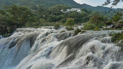 A stormy mountain river. Powerful streams of water foam on rapids and boulders. Splashes. Close-up....