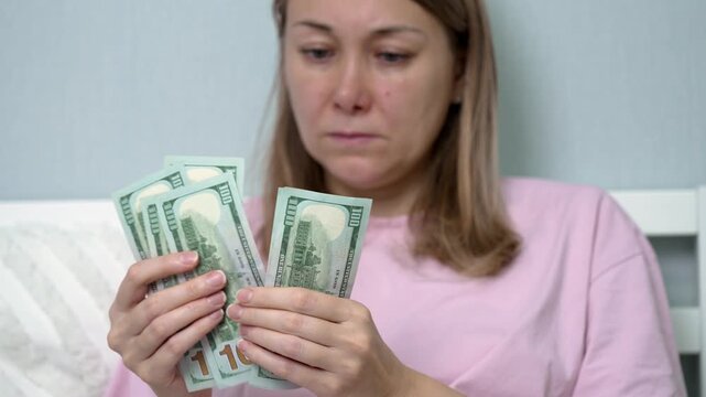 In a quiet room, a woman with a worried expression sorts through bills, counting money she needs for costly medical treatment. The urgency of health unseen looms over her.