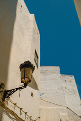 Street lamp attached to whitewashed house exterior in Tangier, minimalist coastal Moroccan architecture.