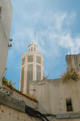 White tower surrounded by clustered old houses in Tangier under clear blue sky, showcasing coastal hillside architecture.