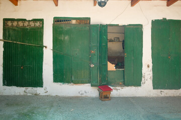 Row of green wooden window shutters on a white wall in Tangier, simple and classic Moroccan street scene.