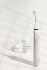 Electric toothbrush with ergonomic handle and blue bristles, placed in a clear glass-ideal for promoting daily oral hygiene in modern bathroom setups.