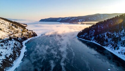 Aerial view of a frozen lake, mountain forests, and mist during winter with soft golden light highlighting the horizon