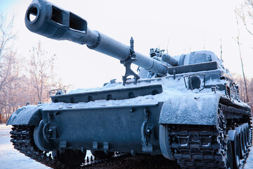 Tank under the snow in the forest. Winter tank camouflage. Battle tank in the snow on the roadside...