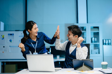 Asian business colleagues celebrating success at work, expressing happiness and motivation after achieving goals in modern corporate office.
