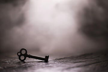 An vintage key on an grungy old desk with a beam of light coming in.
