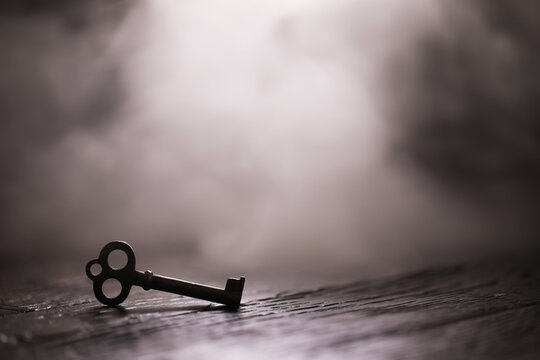 An vintage key on an grungy old desk with a beam of light coming in.