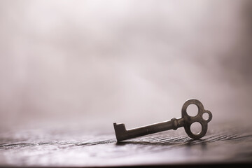 An vintage key on an grungy old desk with a beam of light coming in.