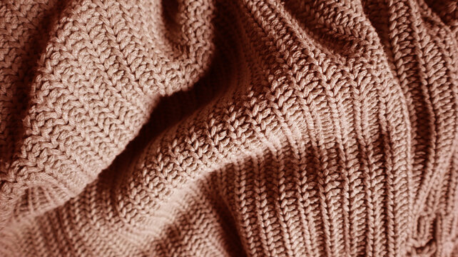 Close up of a knitted blanket or sweater texture in a beige, dusty rose, or terracotta color. Cozy, warm background for autumn, winter, or holiday concepts. Hand knitted, vertical stitch pattern.
