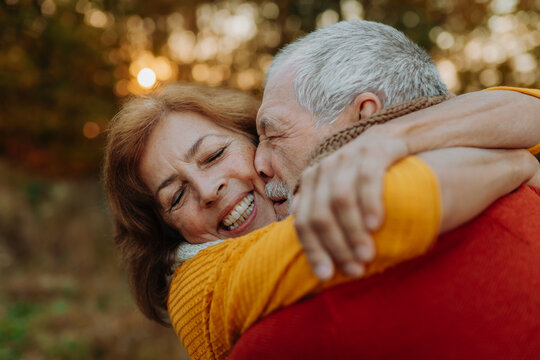 Romantic moment between senior couple, standing in autumn nature.
