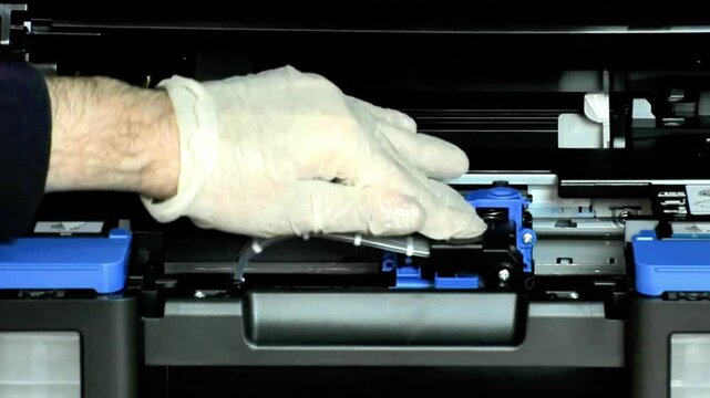 Watch a technician perform precise printer maintenance, installing a new ink system with specialized gloves to ensure optimal performance and avoid contamination