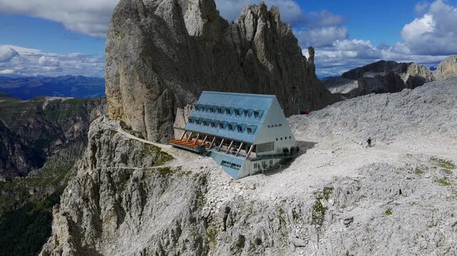 Aerial drone view of Rifugio Passo Santner mountain refuge in Catinaccio Rosengarten group, hikers on trail in Dolomites, Italian Alps