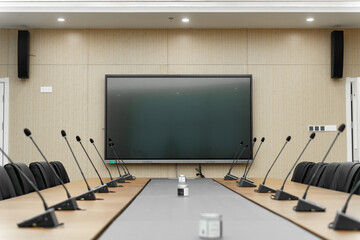 modern conference room with a large screen, multiple microphones